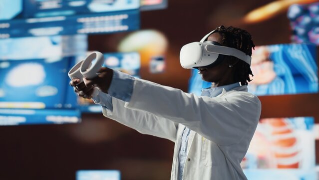 Virtual reality technology used by healthcare expert looking at CT scans, MRI data, and lab analytics on videowall. Scientist in medical research lab reading health data with VR goggles gear, camera B