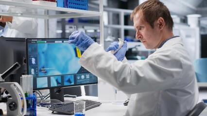 Researcher in clinical laboratory prepares solution with pipette and jars, mixing matter for...