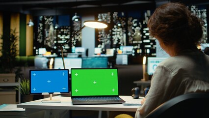 Executive manager at desk uses green screen on laptop and blue screen on tablet, scheduling new meetings and planning the weekly agenda. Business management tasks for a project. Camera A.