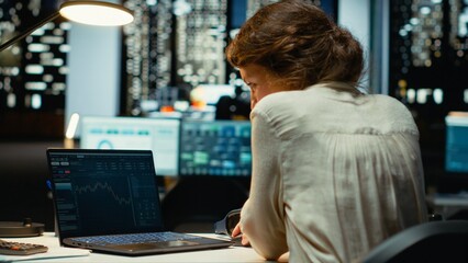 Professional worker in office monitors stock trends and candlestick charts on laptop, using data analysis, forecasting and finance strategy to optimize trading and achieve revenue goals. Camera B.