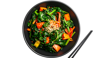 Top-down view of a vibrant green spinach and carrot dish in a black bowl with chopsticks