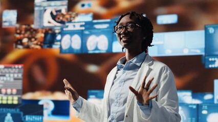 Smiling healthcare researcher mesmerized by futuristic medical data visualizations, working on disease prevention research. Scientist awed by high tech patient scans on digital interface, camera B