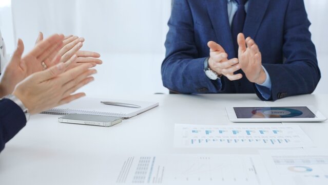 Professional business team clapping hands, celebrating successful presentation, showcasing collaborative spirit and corporate achievement in modern meeting space