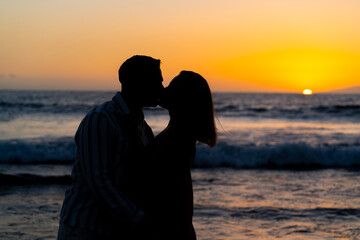 Silhouette of a loving couple kissing on the beach at sunset