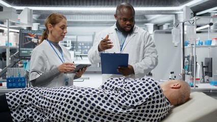 Obraz premium Diverse healthcare workers examine a patient during a drug trial, monitoring treatment outcomes, side effects and dosage response. Advancing medicine and health innovation. Camera A.