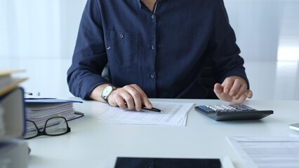 Professional businessman calculating financial data, reviewing documents near laptop in modern workplace setting. Audit and taxes, business concept