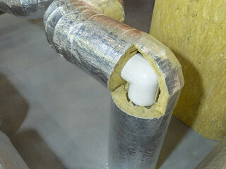 Thermal insulation of pipeline with mineral wool and foil coating, protecting plastic pipe joints for energy efficiency and heating system durability.