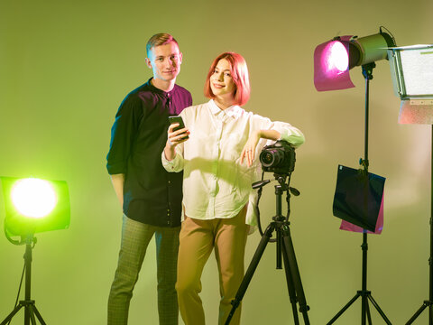 Photographers adjust lighting setup and camera for a studio photoshoot, preparing professional equipment, creative shooting process, and visual production. - Powered by Adobe