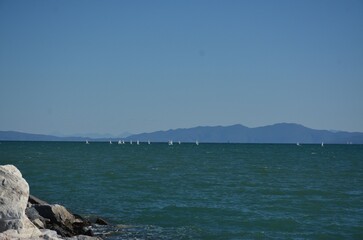 Blue-green sea, sailboats and small mountains in the distance