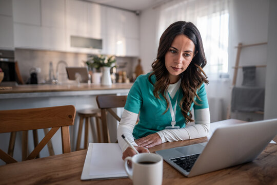 Female nurse working from home using laptop