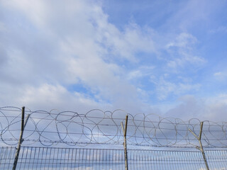 barbed wire fence against blue sky