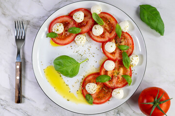 Caprese salad with tomatoes, mozzarella cheese and basil on a white plate