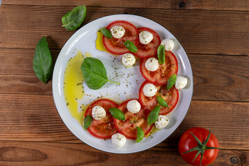 Caprese salad with tomatoes, mozzarella cheese and basil on a white plate