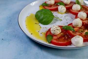 Caprese salad with tomatoes, mozzarella cheese and basil on a white plate
