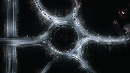 Canvas schilderij Snelweg bij nacht Nighttime aerial view of a roundabout with glowing car light trails creating a dynamic cityscape.  © Pavel Babic