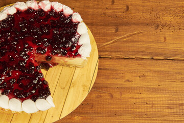 Cheesecake topped with elderberry jelly. Close-up shot on a rustic wooden background with copy space