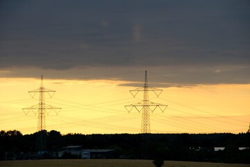 Power line pylons at sunset, electricity grid