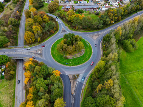 High angle view of cars navigating a roundabout surrounded by colorful autumn foliage