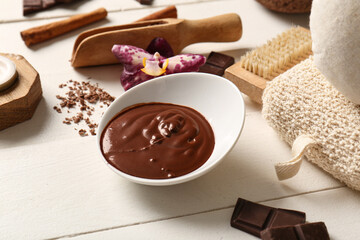 Spa composition with bowl of melted chocolate on white wooden background, closeup