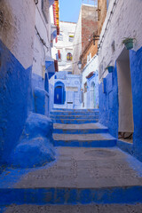 Narrow, cobblestone alley  in the Old Town section of Chefchaouen, Morocco, where homes, walls and steps are painted beautiful shades of blue
