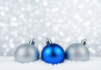 Christmas ornaments in snow with a shimmering silver background
