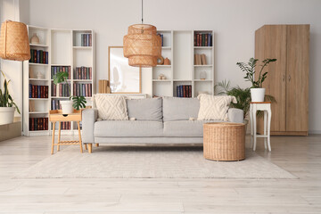 Interior of living room with sofa, table and book shelves near white wall