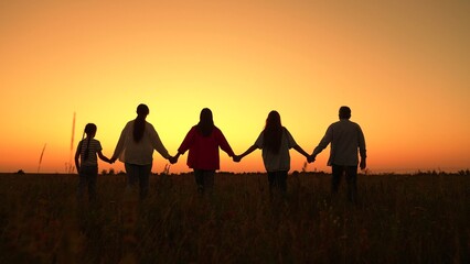 Family group strolling hand in hand in nature. Human resources. Business teamwork, sunset in nature. Group of active people outdoors. Unity among group of people united by idea of working together
