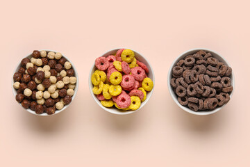 Bowls with cereal rings and corn balls on beige background