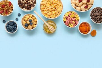 Bowls with different cereals and ingredients on blue background