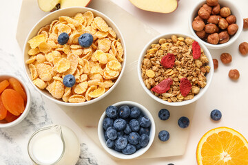 Bowls with different cereals on marble background, closeup