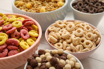 Bowls with different cereals on white wooden background, closeup
