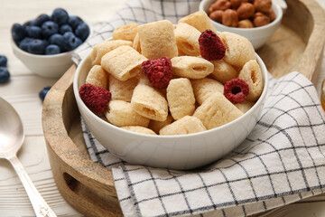 Bowl with corn pillows and berries on white wooden background, closeup