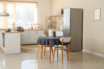 Table with chairs near beige wall in interior of kitchen