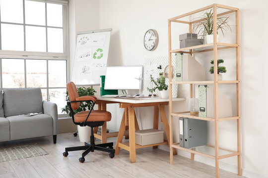 Brown leather swivel chair and workplace with modern computer near white wall in office