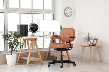 Brown leather swivel chair and workplace with modern computer near window in office