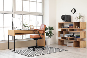 Brown swivel chair and workplace with modern computer near window in room