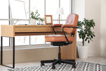 Brown leather swivel chair and workplace with modern computer near window in office