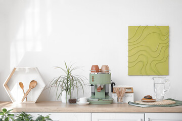 Modern coffee machine, houseplant and jug of water on table in room