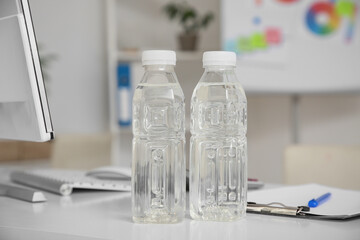 Plastic bottles of water on table in office, closeup
