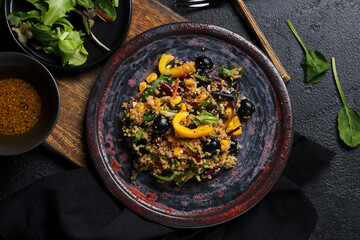 Plate with healthy quinoa salad on black grunge background, closeup