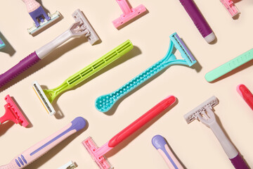 Composition with different disposable shaving razors on beige background, closeup