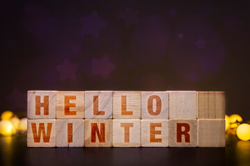 Hello Winter spelled out on wooden blocks with festive lights and star bokeh background, seasonal greeting for cold weather
