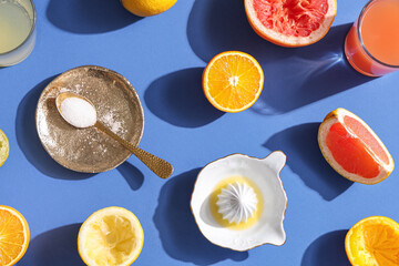 Ceramic juicer and different citrus fruits on blue background, closeup