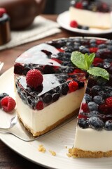 Taking piece of delicious cheesecake with berries at table, closeup