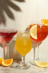 Glasses of tasty cocktails with garnish on white marble table, closeup