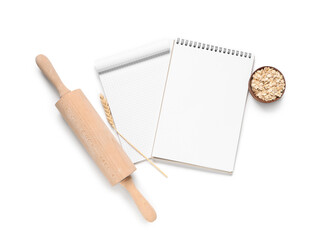 Blank recipe books with rolling pin, spikelet and oatmeal on white background