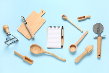 Blank recipe book with wooden kitchen utensils on blue background