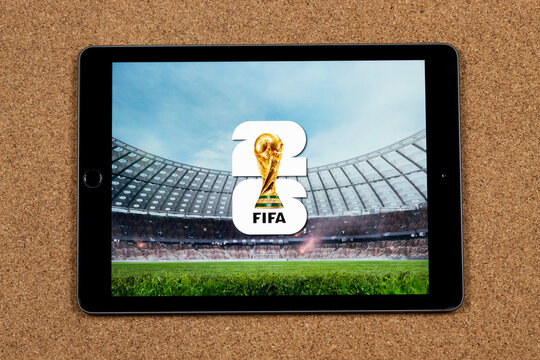 an iPad with the fifa world cup 2026 logo over a blurred stadium and a cork background