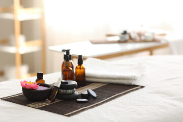 Bamboo mat with spa stones, sea salt and cosmetic products on couch in salon