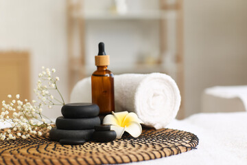 Spa stones with towel, plumeria flower and cosmetic product on couch in salon
